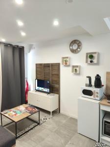 a living room with a table and a clock on the wall at studio proche du marché de Noël de Strasbourg in Schiltigheim