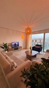 un salon avec un canapé et une télévision dans l'établissement Taghazout Bay Getaway Beach, à Taghazout