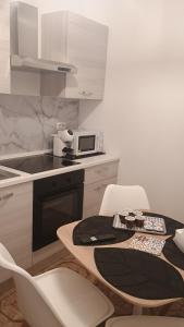 eine Küche mit einem Tisch mit Stühlen und einer Mikrowelle in der Unterkunft CarolHouse in Lido Conchiglia