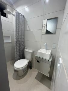 Un baño blanco con inodoro y lavabo. en Suíte com Ventilador e cozinha, en São Pedro da Aldeia