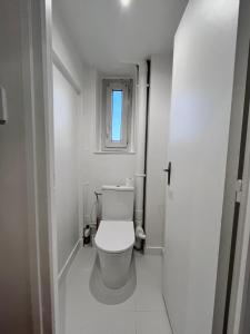 a white bathroom with a toilet and a window at Agréable appartement neuf et lumineux in Saint-Ouen-lʼAumône