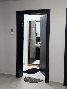 una porta nera che conduce a un bagno con un lavandino di Stan na dan Flower a Šabac