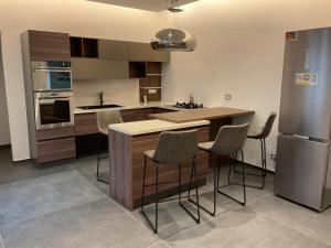 a kitchen with a island with chairs and a refrigerator at La residenza in Nardò