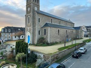 a large brick church with a clock tower on a street at Appartement avec vue mer et plage in Dinard