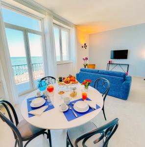 comedor con mesa con sillas y sofá azul en L'Ancora appartamenti 2, en Giovinazzo