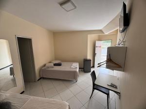 a room with a bed and a table and a television at Pousada Casa Bela in Campina Grande