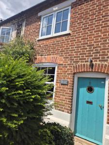 ein Backsteinhaus mit blauer Tür in der Unterkunft Lime Kiln Quay Cottage in Woodbridge