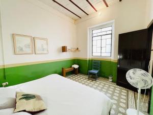 a bedroom with a white bed and a green wall at Departamento #8 frente al Zócalo de Puebla en casona del siglo XVI in Puebla