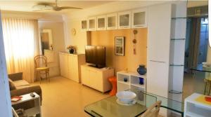 a living room with a table and a television at Flat em Boa Viagem in Recife