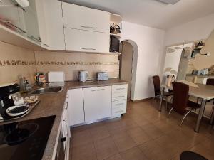 a kitchen with white cabinets and a table with chairs at Ana's Garden Sibiu in Sibiu