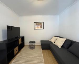 a living room with a black couch and a flat screen tv at Casa da Avó Joaquina in Colares