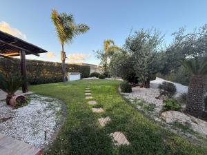 a garden with palm trees and grass and rocks at Villa Sole in Petrosino