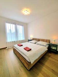 a bedroom with a large bed with two red towels on it at Downtown New Apartment Free Parking in Nivy