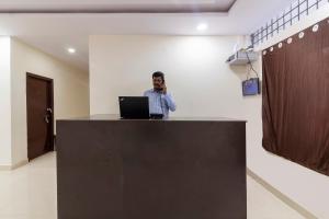 a man standing at a counter with a laptop at Hotel O Shannu Residency in Secunderabad