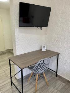 a wooden table with a chair and a television on a wall at Hotel Farallon Inn Cancún in Cancún