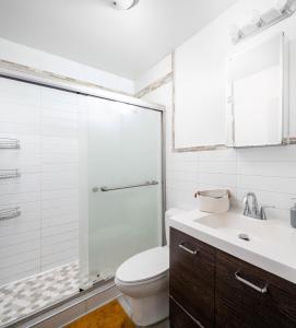 a bathroom with a toilet and a glass shower at Spacious 3BR Retreat Near Times Square in New York