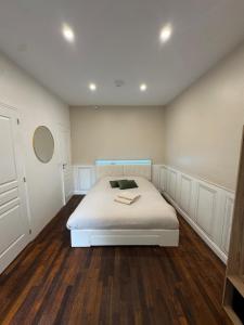 a bedroom with a white bed with a wooden floor at Le Cottage du Centre in Boulogne-sur-Mer