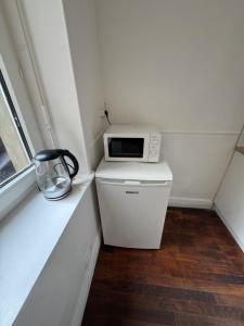 a small kitchen with a microwave on top of a refrigerator at Le Cottage du Centre in Boulogne-sur-Mer