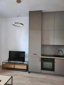 a kitchen with white cabinets and a tv and a table at Apartament przy parku in Słupsk