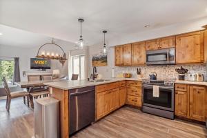 Una cocina con gabinetes de madera y electrodomésticos de acero inoxidable. en 500 Vasquez Road #5 3BR Townhome in Downtown Winter Park with Deck, en Winter Park