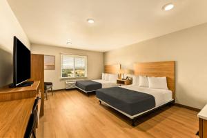 a hotel room with two beds and a flat screen tv at LivAway Suites Salt Lake City- Draper in Draper
