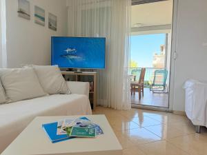 a living room with a white couch and a tv at Balaton BeachSide Apartman Siófok N2 in Siófok
