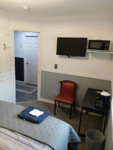 a room with a bed and a television and a chair at Aurora Nights in Fairbanks