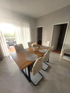 a dining room with a wooden table and white chairs at Apartman Silvija Čiovo in Slatine