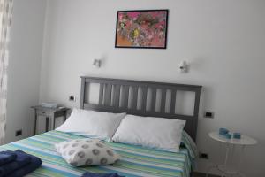 a bed with two pillows and a picture on the wall at Appartamento Lungomare Toscanelli in Lido di Ostia +50 photos