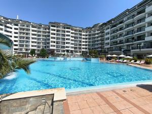 a large swimming pool in front of a large apartment building at Emerald Apartman Wellness & Spa in Ravda