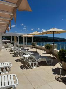a row of white chairs and umbrellas on a patio at SF Apartments Lux in Dobra Voda