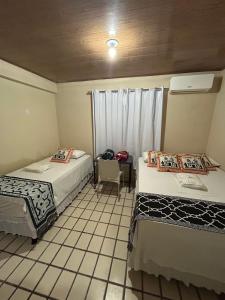 a room with two beds and a table with a chair at Pousada dos Artistas unidade 2 in Campina Grande