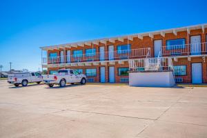 a building with two trucks parked in a parking lot at OYO Crossroads Inn in Osborne
