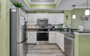 a kitchen with white cabinets and a stainless steel refrigerator at Beach Vibes Condo in Gulf Shores