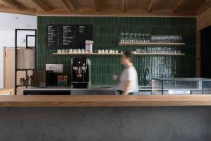 a man standing at the counter of a coffee shop at Hotel ÜJA in Scuol