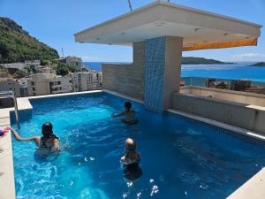 three children swimming in a swimming pool on top of a building at Lunde Sea View Apartment in Rafailovici