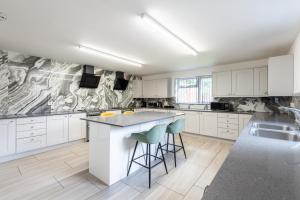 a kitchen with white cabinets and a island with bar stools at Contractor Stay and Holiday Let - Sleeps 2 in Coventry