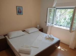 a bedroom with a bed with white sheets and a window at Apartman Silvija Čiovo in Slatine