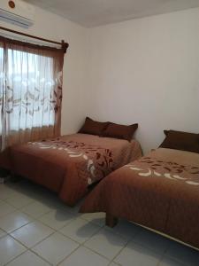 Dos camas una al lado de la otra en una habitación. en Casa Laura, en El Venadillo