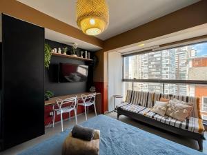 una camera da letto con divano, tavolo e finestra di Belint Bela Cintra: A 5 Minutos da Paulista com Piscina no Rooftop a San Paolo