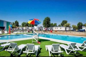 a group of chairs and an umbrella next to a swimming pool at Centrix at Seawick Holiday Park in Saint Osyth