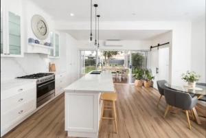 Una cocina con gabinetes blancos y una mesa y sillas. en Kyabram Happy House WIFI Pet Friendly, en Kyabram