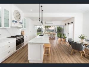 Una cocina con gabinetes blancos y una mesa con sillas. en Kyabram Happy House WIFI Pet Friendly, en Kyabram 15 fotos más
