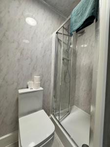 een witte badkamer met douche en toilet bij Oxborne Rooms UK - Plaistow in Londen +2 foto's