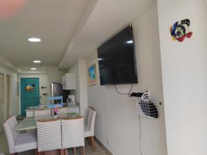 a dining room with a table and a television on a wall at Beautiful Beach in El Quindio +7 photos
