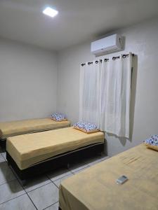 a room with two beds and a window with a air conditioner at Casa Sítio in Rio Verde