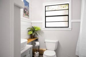 a bathroom with a toilet and a sink and a window at The PanAm fire pit bbq kid & dog friendly in Pensacola