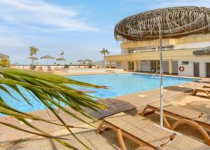 a swimming pool with chairs and a building at Luxury Sunset 408 heated pool with air condition and sea views in Adeje