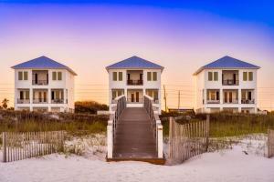 a boardwalk leading to two houses on the beach at Whitecap - Beachfront Gem with Pool & Elevator in Orange Beach