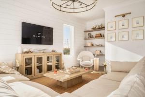 a living room with a white couch and a tv at Whitecap - Beachfront Gem with Pool & Elevator in Orange Beach